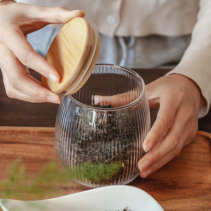 Opening the bamboo lid of a tea caddy filled with loose-leaf tea