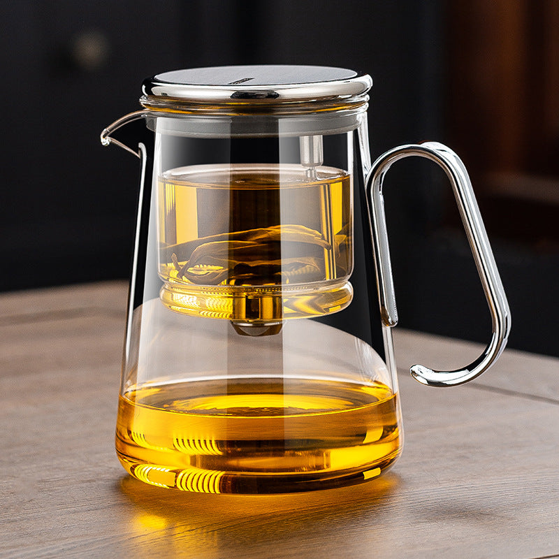 The Lumen Teapot in clear glass with silver trim, tea steeping in the glass infuser