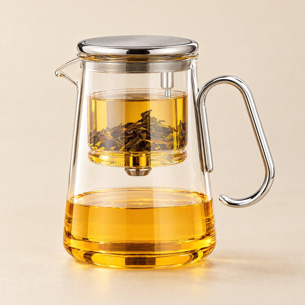 The Lumen Teapot in clear glass with silver trim, filled with golden oolong, on a cream background