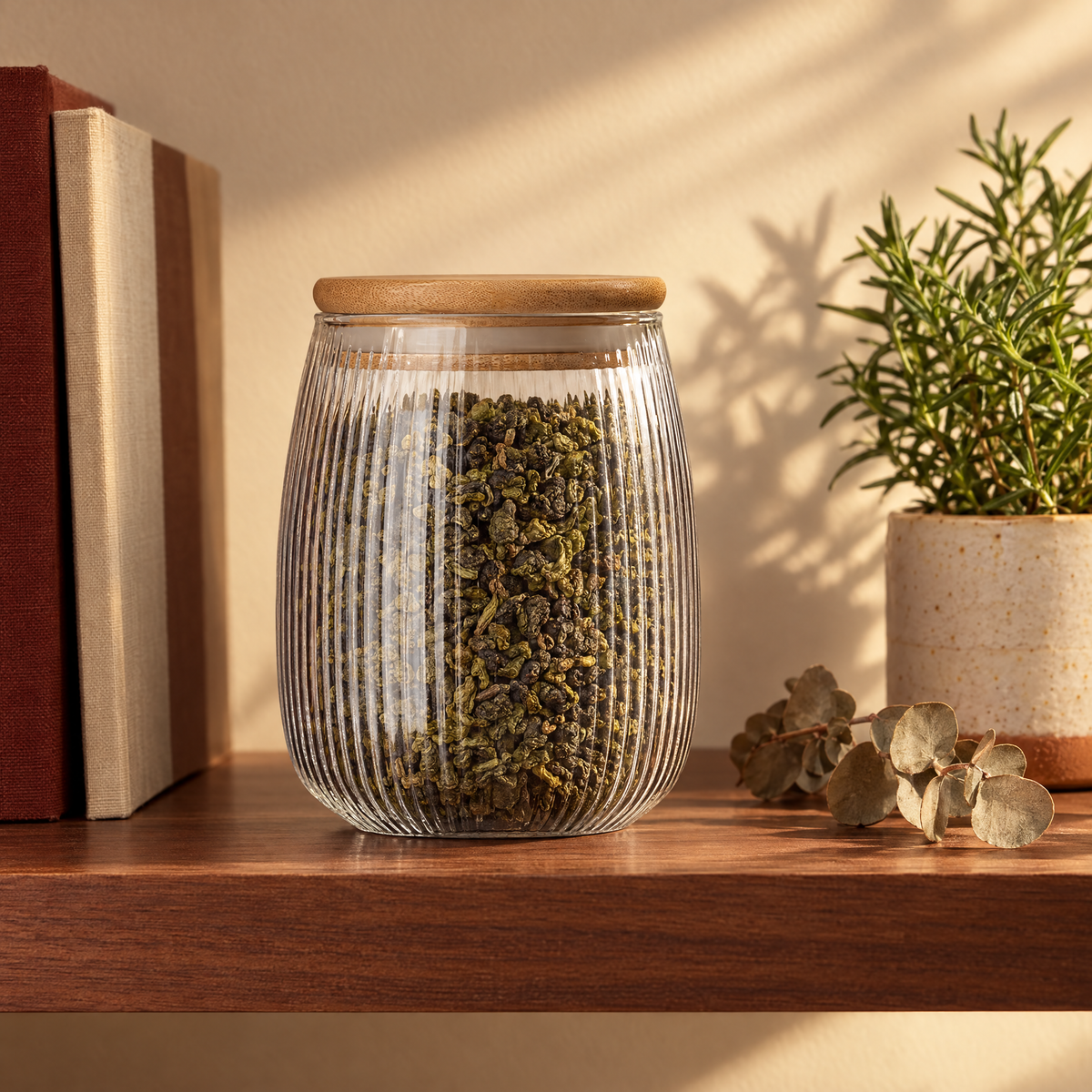 The ribbed glass tea caddy full of oolong on a walnut kitchen shelf